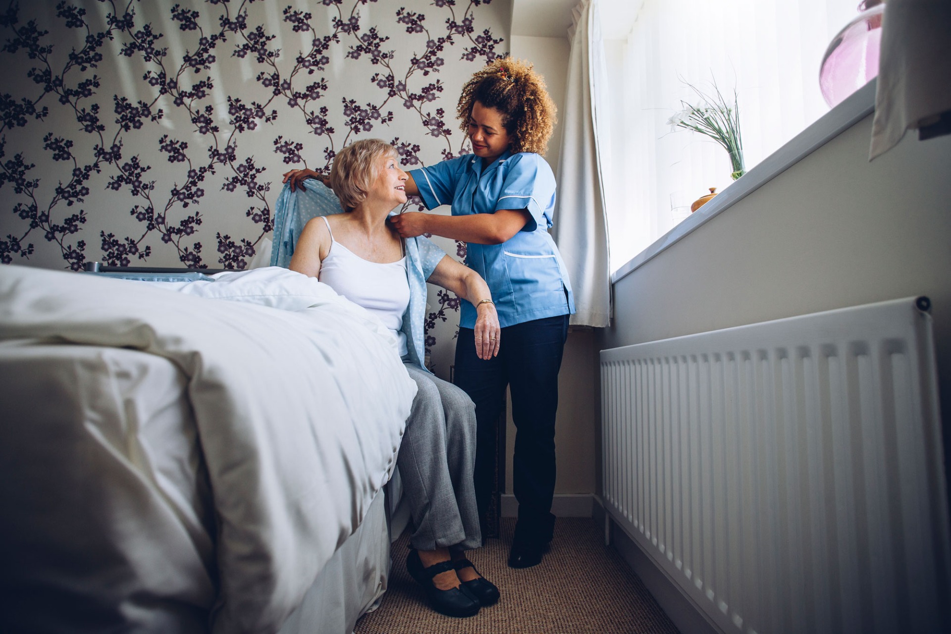 Two elderly women speaking with a carer about domiciliary care