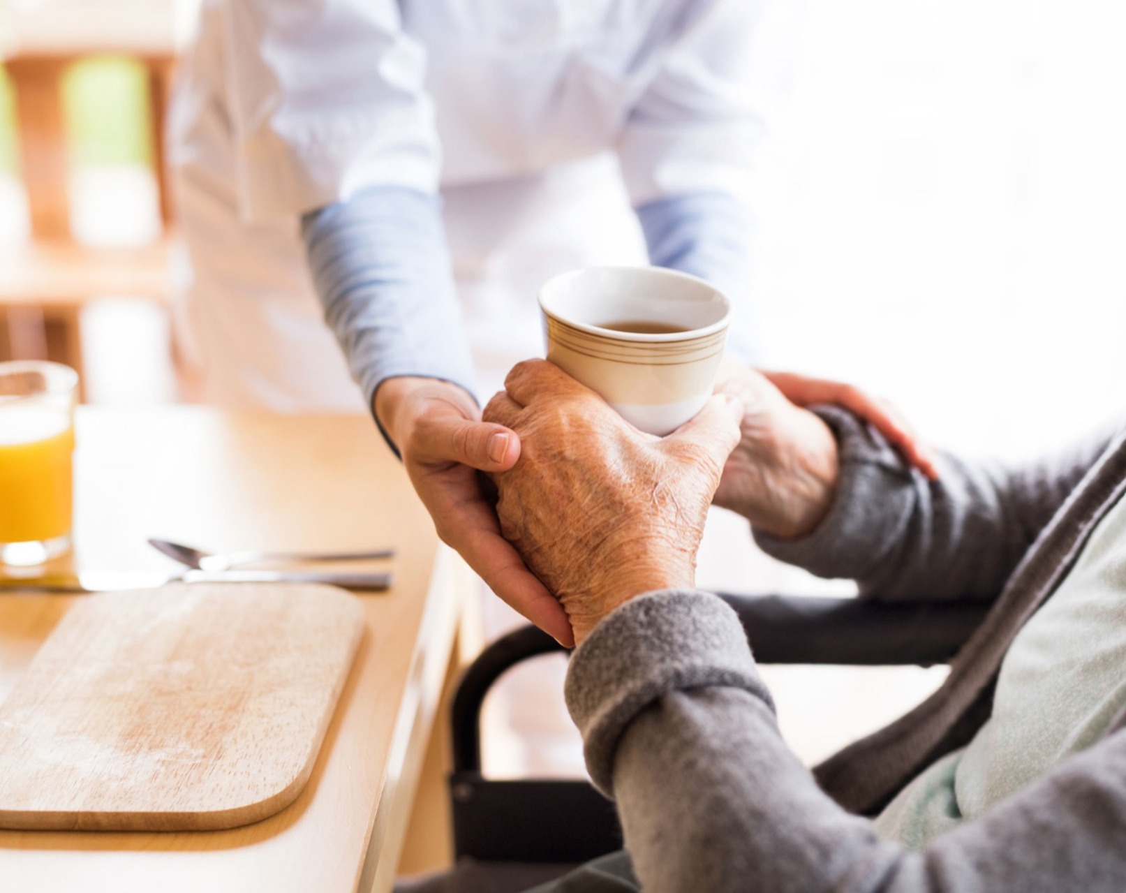 A carer, offering home help, handing over a coffee to an elderly woman